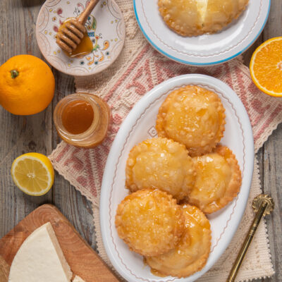 piatto da portata con seadas, miele, formaggio e agrumi