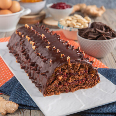 Torta al cioccolato con mandorle su piatto rettangolare bianco con ciotoline con pezzi di cioccolato, mandorle, confetture e uova intere