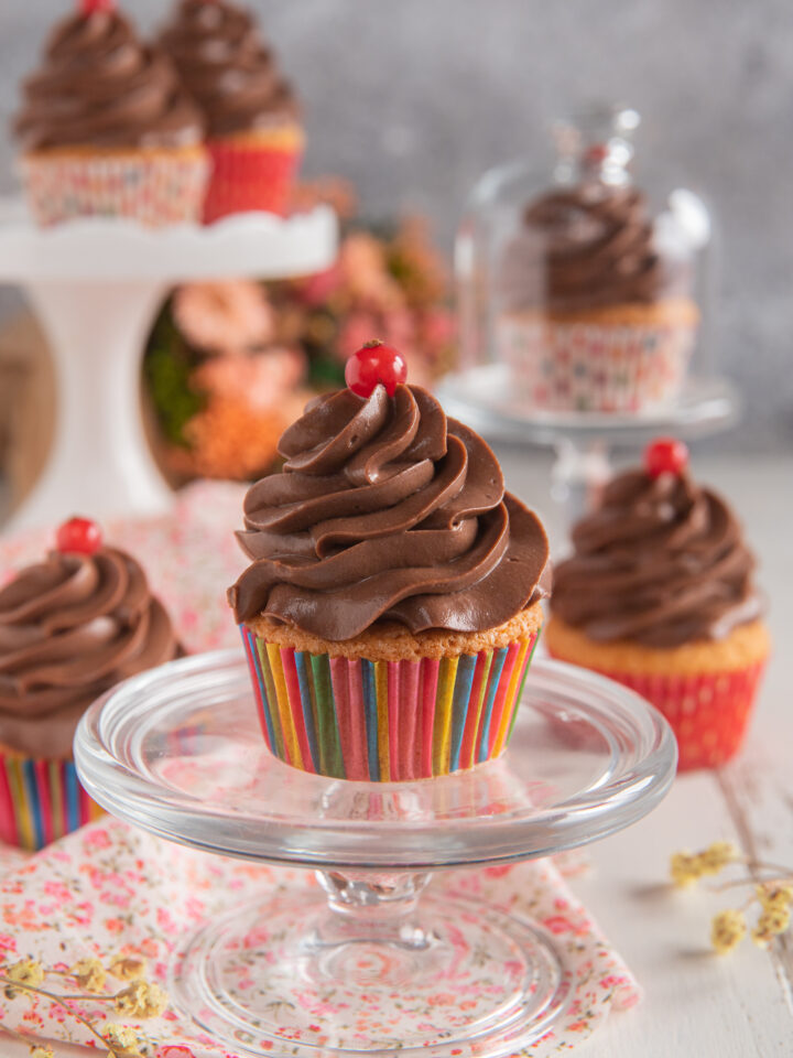 alzatina di vetro con cupcakes, frosting al cioccolato e ciliegina candita