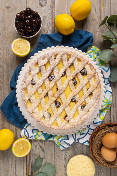 La crostata amalfitana è un dolce che unisce alcune delle preparazioni base della pasticceria, come pasta frolla e crema pasticcera, con in più il tocco delle amarene sciroppate