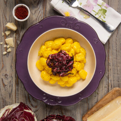 Gli gnocchi radicchio e zafferano sono un piatto semplice ma anche colorato e avvolgente, in cui una cremosa crema dorata avvolge i classici gnocchi di patate e in cui la punta piacevolmente amara del radicchio saltato rende tutto più interessante