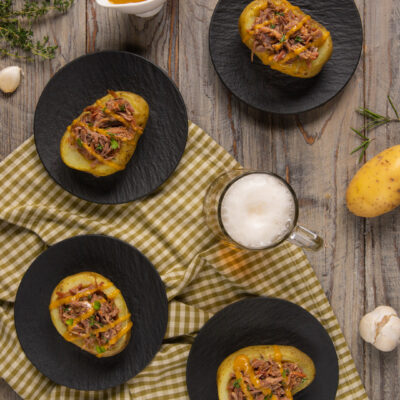 Le patate ripiene di stinco sfilacciato con salsa alla birra sono un secondo piatto di carne semplice da preparare ma molto scenografico, ideale da servire anche sulla tavola delle Feste