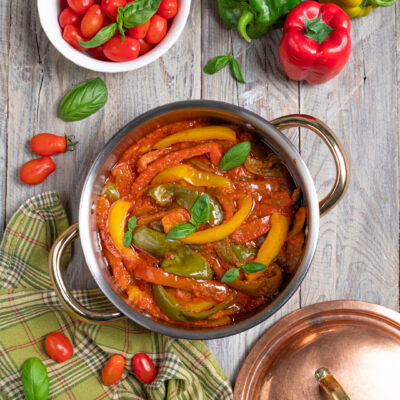 Un delizioso contorno vegetariano con i colori del sole e il profumo d'estate mediterranea, a base di peperoni, pomodori e basilico