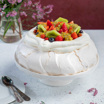 Una torta a base di meringa alla francese dal cuore morbido, impreziosita da panna montata e frutta fresca