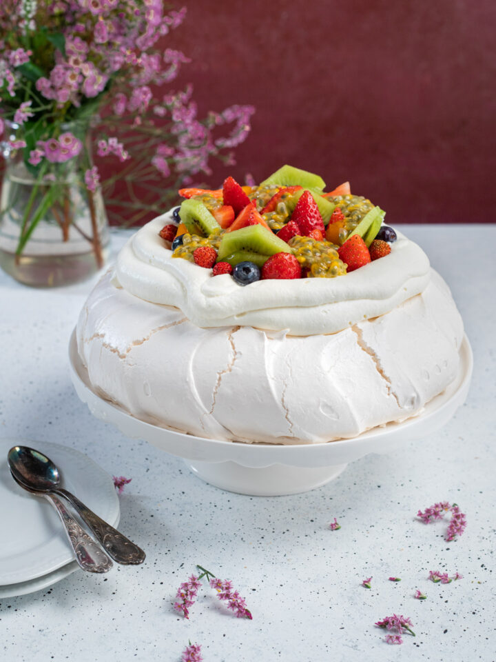 Una torta a base di meringa alla francese dal cuore morbido, impreziosita da panna montata e frutta fresca