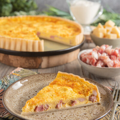 Una torta salata tipica della cucina, composta da un guscio di pasta brisée che racchiude un ripieno a base di panna, pancetta e formaggio