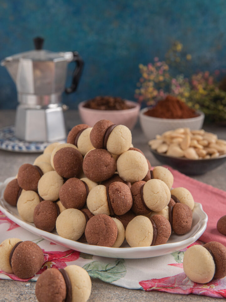 Friabili biscottini composti da due semisfere di pasta frolla alle mandorle aromatizzate alla vaniglia e al cacao e tenute insieme da una ganache al cioccolato e caffè