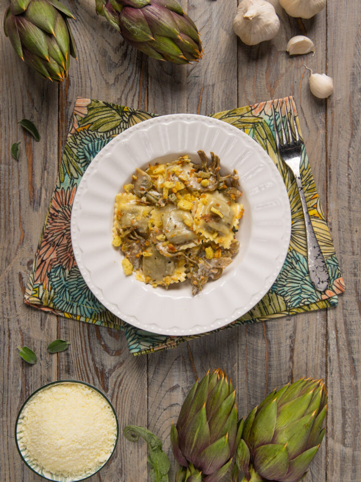 Un primo piatto di pasta fresca ripiena di brasato al barolo, abbinata a un condimento primaverile a base di carciofi e di fonduta di pecorino