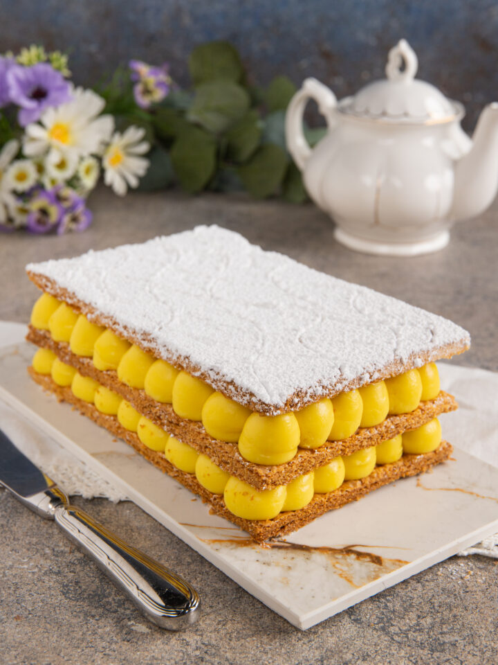 Un dolce a strati composto da cialde croccanti di pasta sfoglia e una farcitura di crema pasticcera. Il tutto decorato con una spolverata di zucchero a velo