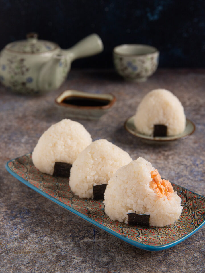 Gli onigiri sono una tipologia di sushi costituita da polpette di riso a forma triangolare con un ripieno di salmone e parzialmente avvolte da una striscia di alga Nori che le rende facili da mangiare con le mani