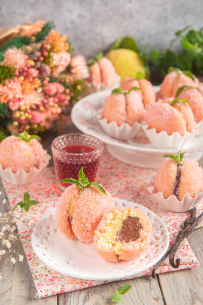 Due cupole di morbido biscotto coperte di zucchero e aromatizzate all'Alchermes con una doppia farcitura alla crema pasticcera in versione classica e al cioccolato