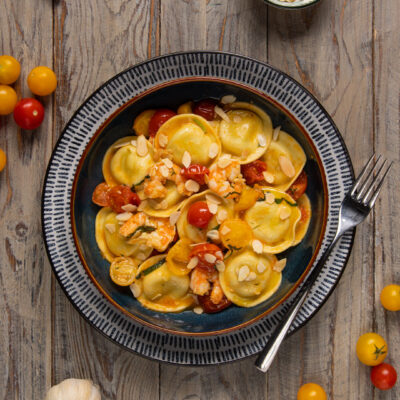 I ravioli agli asparagi con gamberi marinati e pomodorini sono un primo piatto di pasta ripiena capace di portare in tavola tutto il profumo del mare e il gusto della primavera