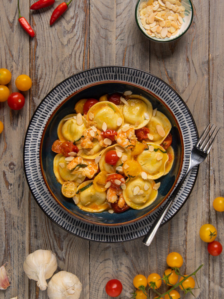 I ravioli agli asparagi con gamberi marinati e pomodorini sono un primo piatto di pasta ripiena capace di portare in tavola tutto il profumo del mare e il gusto della primavera