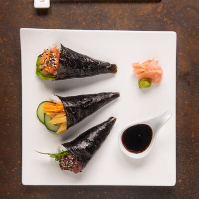 I temaki sono un tipo di sushi a forma di cono di alga Nori ripieno di riso, pesce e verdure, fritttata giapponese, wasabi e semi di sesamo