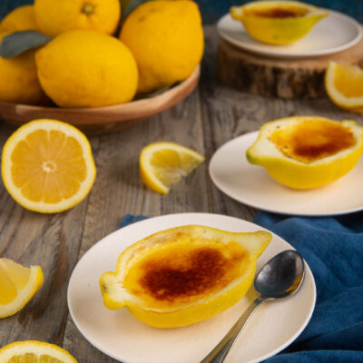 Un dolce al cucchiaio fresco e scenografico, che si prepara come una crema pasticcera profumata al limone e si serve nella scorza di mezzo agrume con una leggera crosticina caramellizzata in superficie.
