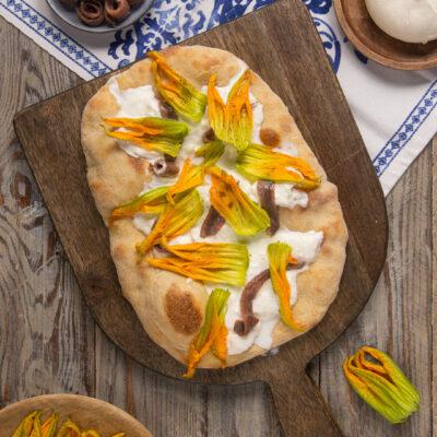 Un lievitato tipico della cucina laziale, che assomiglia un po' a una pizza, un po' a una focaccia, farcito in superficie con alici, fiori di zucca e burrata