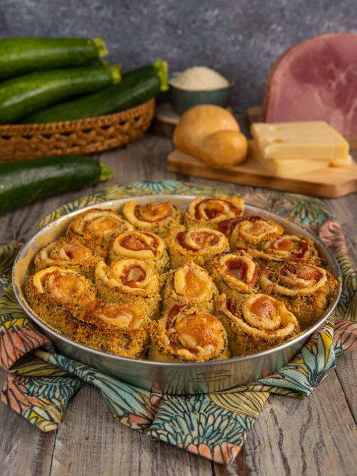 Un simpatico antipasto a base di zucchine tagliate a fette, prosciutto cotto ed Emmental, impanate e cotte al forno