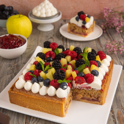 Una torta di compleanno a base di pasta frolla, confettura di lamponi, frangipane alle mandorle e tanta frutta fresca e colorata