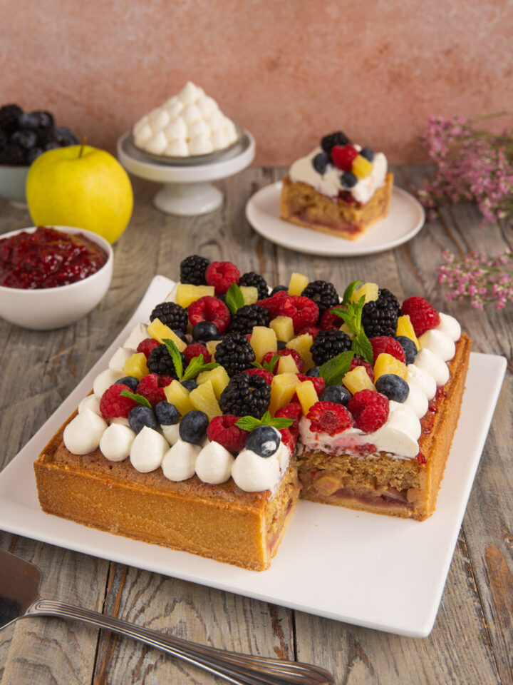 Una torta di compleanno a base di pasta frolla, confettura di lamponi, frangipane alle mandorle e tanta frutta fresca e colorata