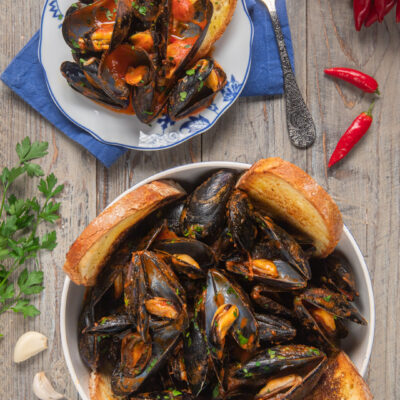 Le cozze alla tarantina sono un delizioso antipasto pugliese, in cui questo saporito mollusco viene condito con una salsa al pomodoro piccante, in cui intingere il rustico pane di Altamura