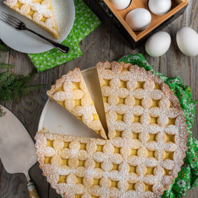 La crostata con la crema pasticcera è un dolce semplicissimo da preparare, con una base di pasta frolla, una farcitura vellutata profumata alla vaniglia e limone e una bella decorazione in superficie