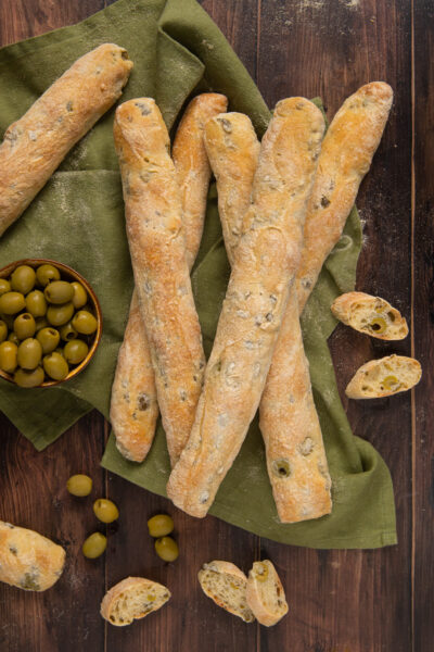 I filoncini alle olive sono un lievitato saporito ideale da presentare nel cestino del pane, in cui al gusto neutro dell'impasto vengono aggiunge le olive per una spinta di sapore in più