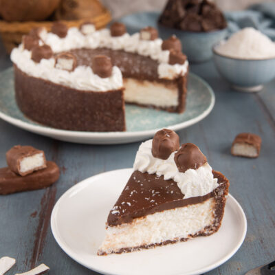 Un dolce fresco dal gusto tropicale, che si prepara come una cheesecake, con un fondo di biscotti, una crema al cocco e una copertura di ganache al cioccolato, panna montata e cioccolatini al cocco