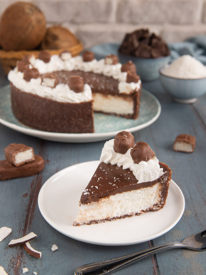 Un dolce fresco dal gusto tropicale, che si prepara come una cheesecake, con un fondo di biscotti, una crema al cocco e una copertura di ganache al cioccolato, panna montata e cioccolatini al cocco