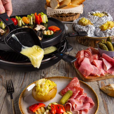 La raclette è un piatto tipico svizzero a base di formaggio fuso, patate al cartoccio, fette di pane, verdure, salumi e sottaceti