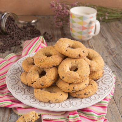 Ciambelline da inzuppo con gocce di cioccolato Questi deliziosi biscotti, preparati con una base che ricorda la pasta frolla e arricchiti da gocce di cioccolato, sono ideali per essere inzuppati nel latte o nel tè, regalando un momento di dolcezza.