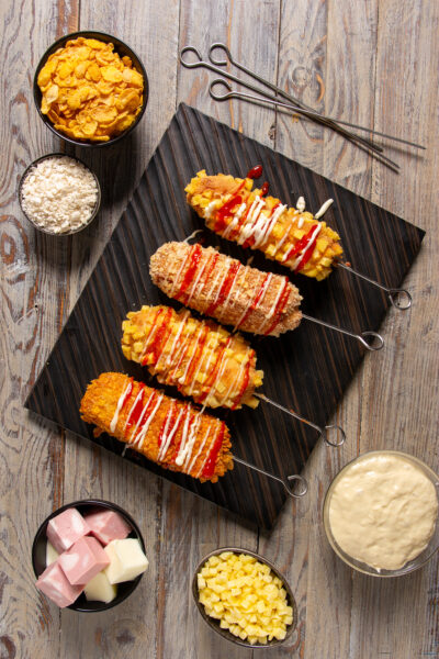 Korean corn dog di mortadella Un particolare hot dog di mortadella e provola avvolte in una pastella lievitata e racchiuse in una croccante panatura