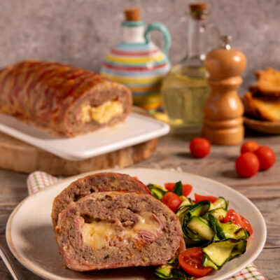 Polpettone di carne vestito Polpettone al forno con involucro di bacon, cuore filante di provola e fontina e impasto ricco di sapori.