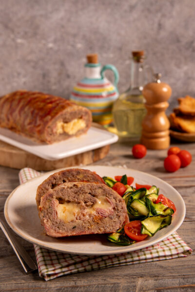 Polpettone di carne vestito Polpettone al forno con involucro di bacon, cuore filante di provola e fontina e impasto ricco di sapori.
